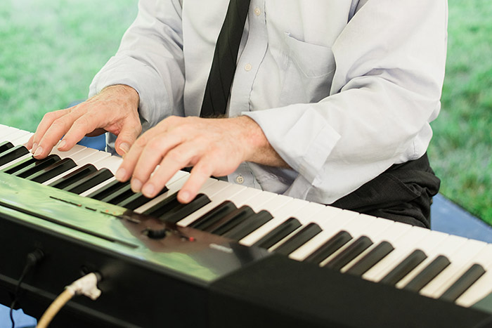 Man playing a keyboard for a wedding reception at Hidden View Farm in Annapolis, Maryland. Photo taken by Carley Fuller.